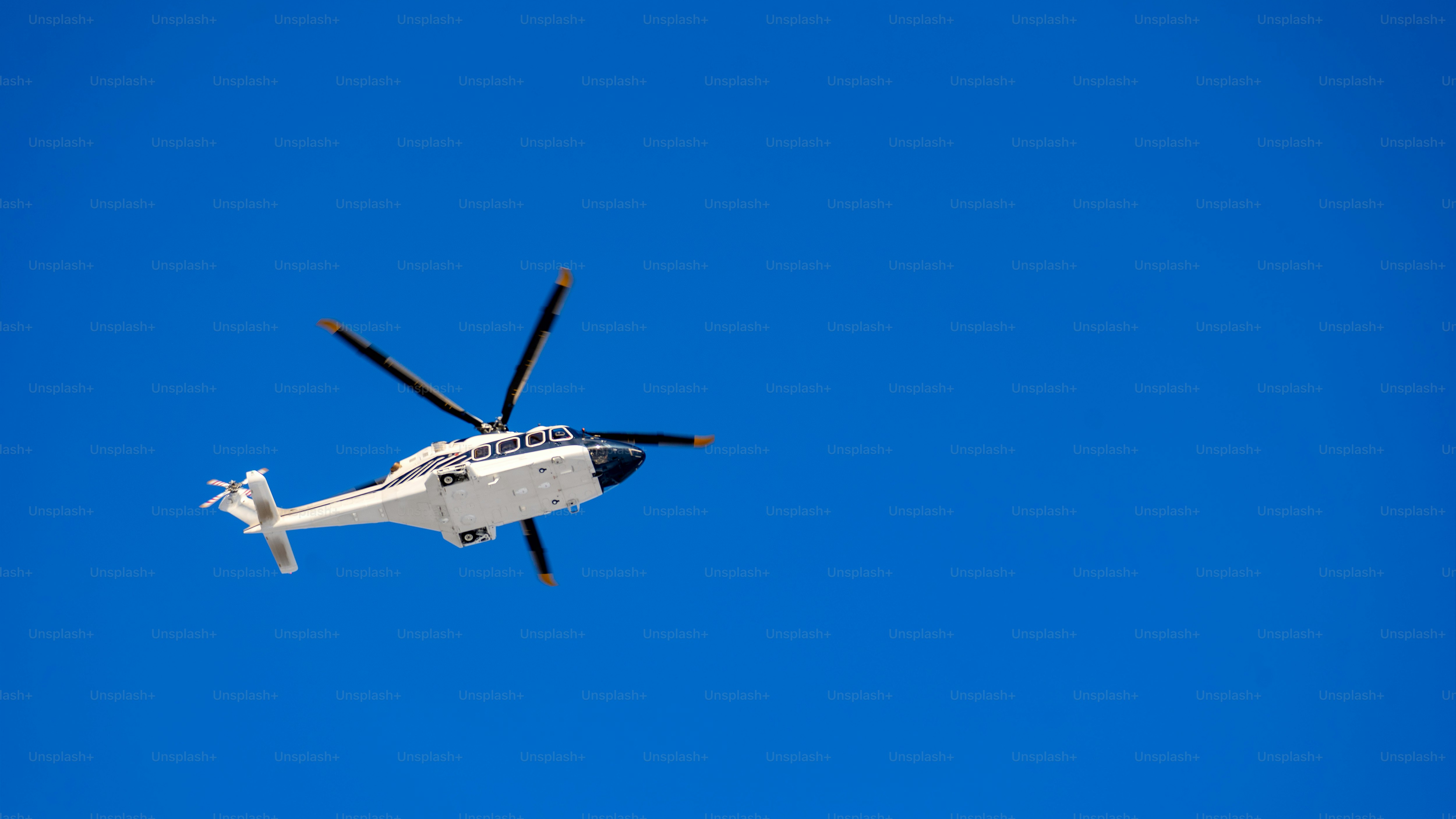 White helicopter on blue sky background, Close-up, selective focus, tinted image. Helicopter flight, delivery of passengers by air.